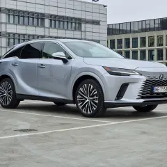 Srebrny Lexus RX350h zaparkowany przed nowoczesnym budynkiem biurowym.