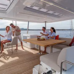 Coppia felice brinda a bordo di un catamarano, godendosi il sole e il mare. Interni eleganti e confortevoli.