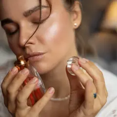 Kobieta wącha perfumy. Czy refill perfumy to sposób na ponowne użycie ulubionego zapachu?