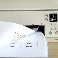Dłoń wsuwa papier do drukarki, na ekranie widoczny numer 1 i opcja "Kopia cz.-biała".
