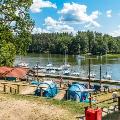 Namioty rozbite nad jeziorem, gdzie cumują żaglówki. Idealne miejsce na wypoczynek, prawdziwy pole namiotowe Mazury.