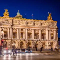 Słynny teatr w Paryżu, Opera Garnier, lśni w nocnym świetle. Złote rzeźby i bogata fasada zapraszają na wieczór pełen wrażeń.