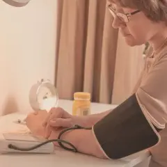 Kobieta mierzy ciśnienie, obok leży lek telmisartan.