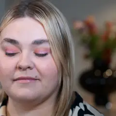 En närbild på en kvinna med rosa skimrande ögonskugga på sina hooded eyes.