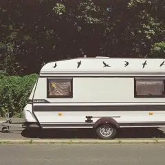 Klasyczna przyczepa kempingowa "Classic" z ptakami na dachu. Idealna na wakacje, można ją ciągnąć na kat B.