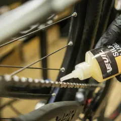 Rękawiczka z czarną rękawiczką aplikuje olej do łańcucha rowerowego. Jaki smar do łańcucha rowerowego wybrać? Ten "Silk Lube" wygląda obiecująco.