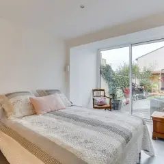 Chambre lumineuse avec vue sur jardin, résultat d'une belle idée : transformer un garage en habitation. Lit douillet, mobilier cosy.