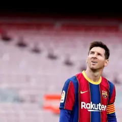Messi w Barcelonie, w swoim charakterystycznym stroju, spogląda w górę na trybuny stadionu.