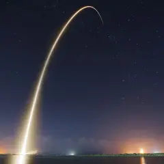 Jasny ślad rakiety wznosi się na nocne, gwieździste niebo, symbolizując start Starlink Elona Muska.