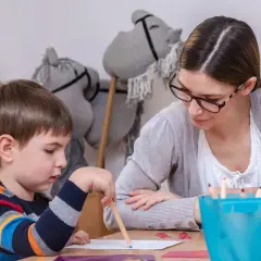 Nauczycielka wspiera chłopca z zespołem Aspergera w rysowaniu. Skupienie na zadaniu, a nie na tym, jak karać dziecko z zespołem Aspergera.