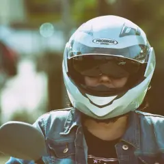 Motociclista con casco jet, che offre una visione chiara, a differenza di un casco demi jet. Indossa giacca di jeans.