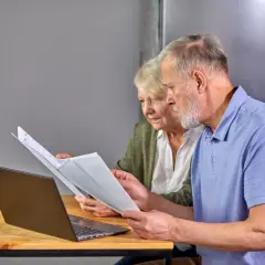 Para seniorów analizuje dokumenty przy laptopie. To przykład ulgi dla seniora w PIT-37.