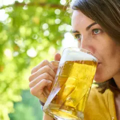 Kobieta pije piwo, zastanawiając się, czy piwo ma dużo kalorii. Orzeźwiający napój w letni dzień.