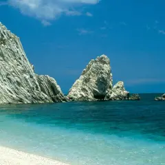Spiaggia bianca e mare cristallino con faraglioni imponenti, un sogno per le vacanze Marche mare.
