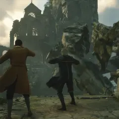 Dwóch uczniów w szatach stoi przed zrujnowaną budowlą na klifie. To scena z gry Hogwart Legacy 2.