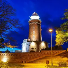 Wieczorem rozświetlone latarnie morskie polska, otoczone drzewami i schodami, tworzą magiczny widok.