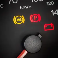 Tableau de bord avec voyant ABS allumé, signalant un problème à tester. Le frein de parking est aussi activé.