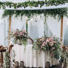 Udekorowany bukietami kwiatów stół i krzesła tworzą romantyczną stylizację boho na wesele.