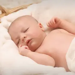 Śpiące dziecko w koszyku, otulone miękkimi kocykami. Marzy o podwójnym becikowym.