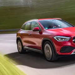 Röd Mercedes GLA på en testkörning längs en grönskande väg.