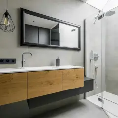 Meuble de salle de bain en bois avec une belle profondeur, miroir, robinetterie moderne et douche vitrée.