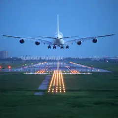 Samolot pasażerski lądujący na pasie startowym o zmierzchu.
