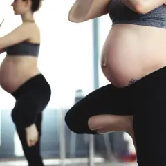 Mujer embarazada haciendo el pino en yoga, con su reflejo en un espejo.