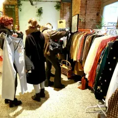 W sklepie z odzieżą vintage, gdzie króluje styl retro, kobiety przeglądają ubrania. To właśnie co oznacza słowo vintage – moda z minionych dekad.