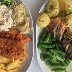 Dwa talerze pysznego jedzenia, idealne pytanie: gdzie zjeść w Gdyni? Ryba z ziemniakami i fasolką, a obok panierowany filet z frytkami i surówkami.