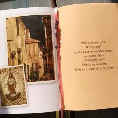 Otwarta książka z obrazkami włoskiej uliczki i postacią Matki Boskiej, obok tekst modlitwy.
