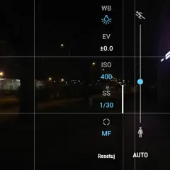 Ekran telefonu z widokiem nocnym. Ustawienia aparatu pokazują, jak ustawić długi czas naświetlania. Widoczny tryb manualny (M) i czas 1/30s.