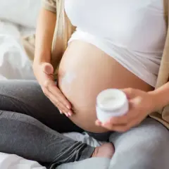 Gravid kvinna smörjer magen med kräm. Vissa krämer innehåller salicylsyra, vilket kan vara bra att veta för dig som är gravid.