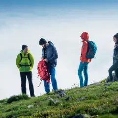 Cztery osoby w górskim krajobrazie, przygotowujące się do wyprawy. To właśnie jest trekking – przygoda na szlaku!