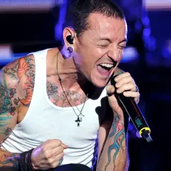Chester Bennington, wokalista zespołu, śpiewa z pasją na koncercie. Jego ramiona pokryte są kolorowymi tatuażami.