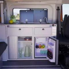Aménagement astucieux de la soute d'un camping-car : cuisine fonctionnelle, réfrigérateur et rangements optimisés pour un voyage serein.