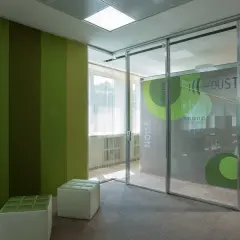 Pannelli verdi a parete e divisori fonoassorbenti creano un ambiente di lavoro moderno e silenzioso.