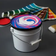 Farbeimer mit verwirbelten Farben, daneben ein Pinsel und Farbfächer. Ideal für eine Tabelle zum Farben selber mischen.