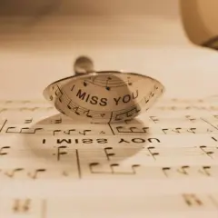 Un anillo con la frase "I MISS YOU" sobre partituras. Un detalle que evoca indirectas y frases de te echo de menos.