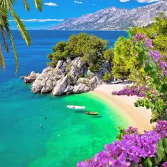 Idealne miejsce, gdzie pojechać na majówkę: rajska plaża z turkusową wodą, łódkami i kwitnącymi bugenwillami.
