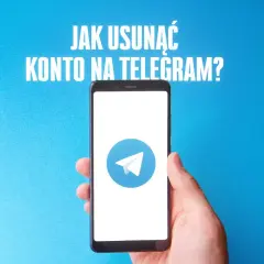 Dłoń trzyma smartfon z logo Telegram na niebieskim tle.