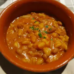 Fagioli in umido, un classico per scoprire cosa mangiare a Piacenza. Serviti in una ciotola di terracotta, sono un piatto saporito e confortante.