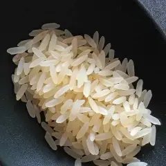 Chicchi di riso originario pronti per la cottura, in una ciotola scura.