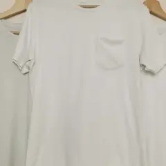 Trois t-shirts blancs sur cintres en bois. Le t-shirt du milieu a une poche poitrine. Idéal pour apprendre comment blanchir un pull blanc.