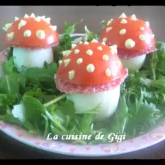 Trois adorables champignon œuf, décorés de tomate et de points blancs, reposent sur un lit de verdure.