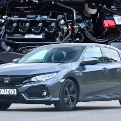 Szary sedan Honda Civic 10 z widocznym silnikiem w tle.