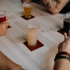 Degustacja piw belgijskich. Na stole cztery szklanki z różnymi piwami: czerwonym, jasnym, miodowym i ciemnym.