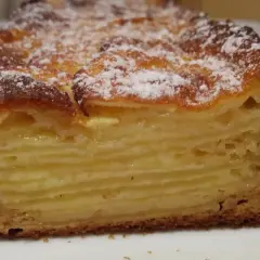 Une tranche de gâteau aux pommes, avec des couches fines et dorées, saupoudrée de sucre glace. Un délice invisible aux pommes.