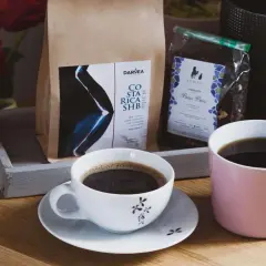 Dwie filiżanki kawy, obok paczki z kawą i herbatą. To idealny zestaw na poranek, by dowiedzieć się, co to jest herbata.
