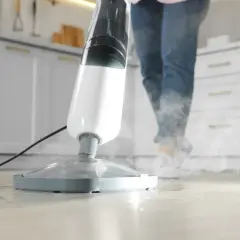 Mop parowy w akcji, para wydobywa się z urządzenia, czyszcząc podłogę.