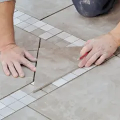 Un carreleur prépare le plan de pose du carrelage, marquant une pièce avec un crayon.